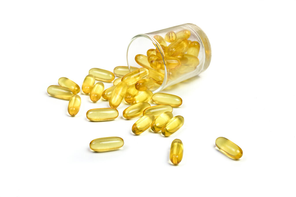 Gold fish oil capsules isolated in a glass bottle on white background. Close up to capsules salmon fish oil view. Supplementary food background. Omega 3. Vitamin E.